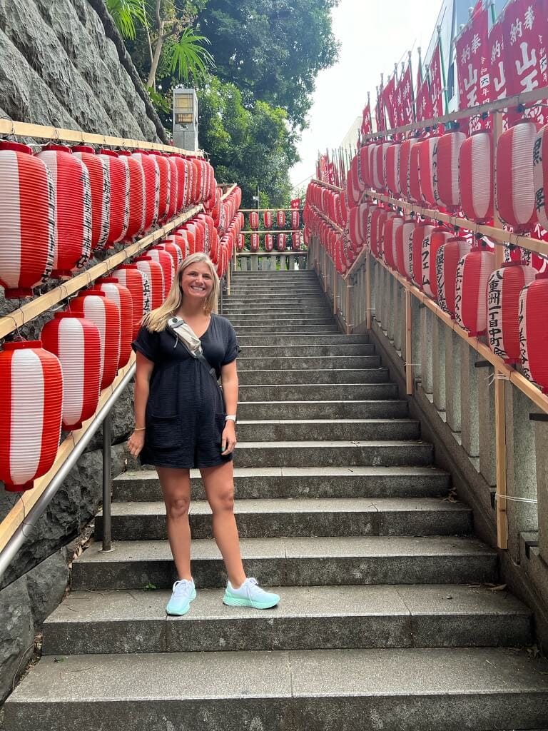 Brenda standing in Tokyo on a stairway lined with lanterns