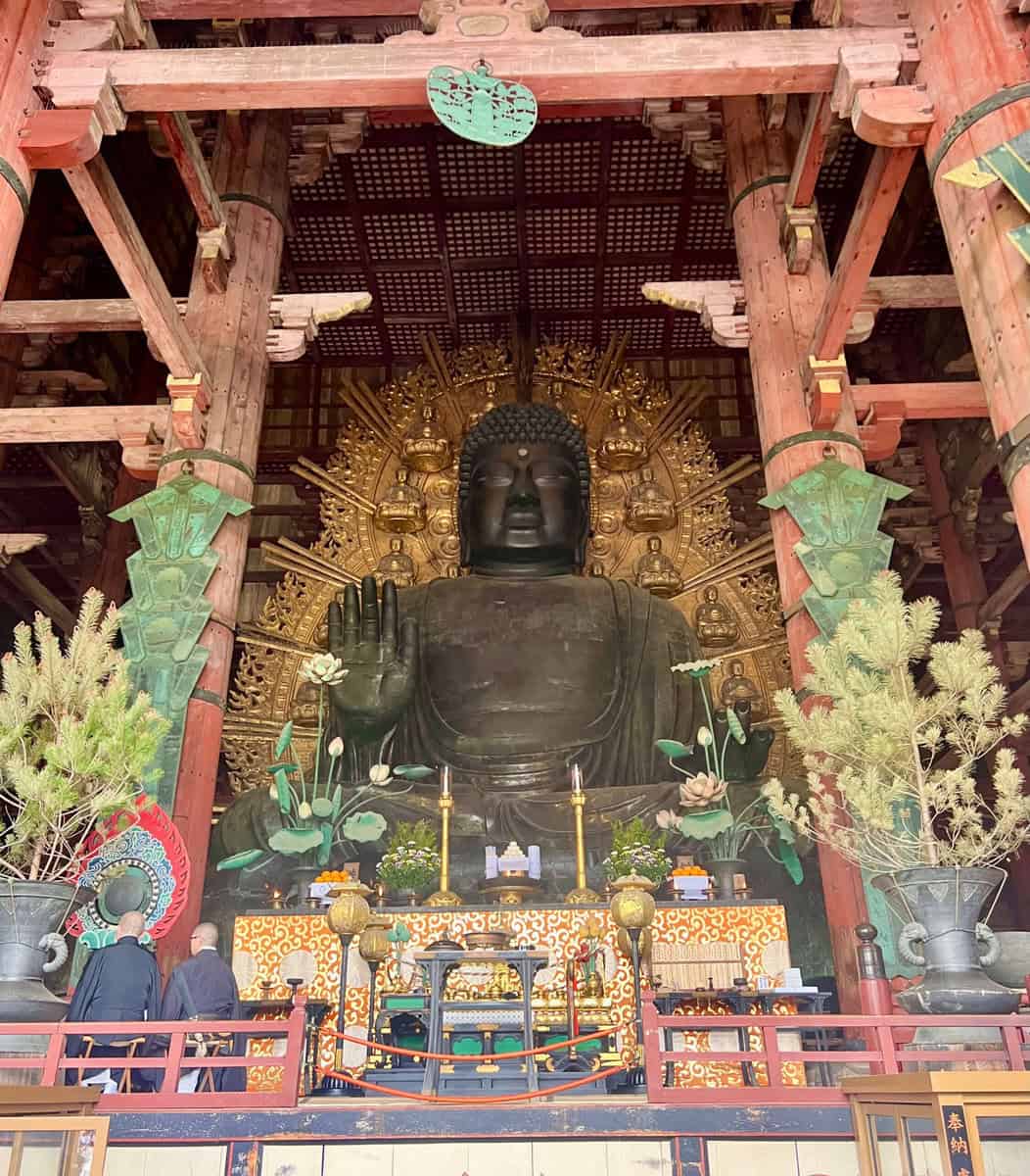 A large buddha statue in a temple with green pillars.