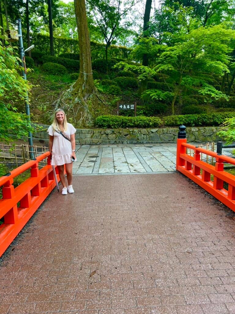 A woman standing on a bridge in a japanese garden.