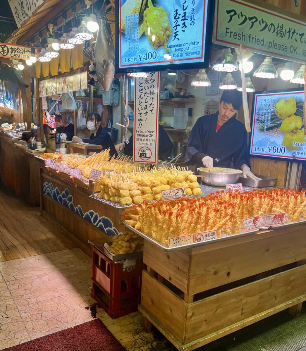 A man standing in front of a display of tempura battered food.
