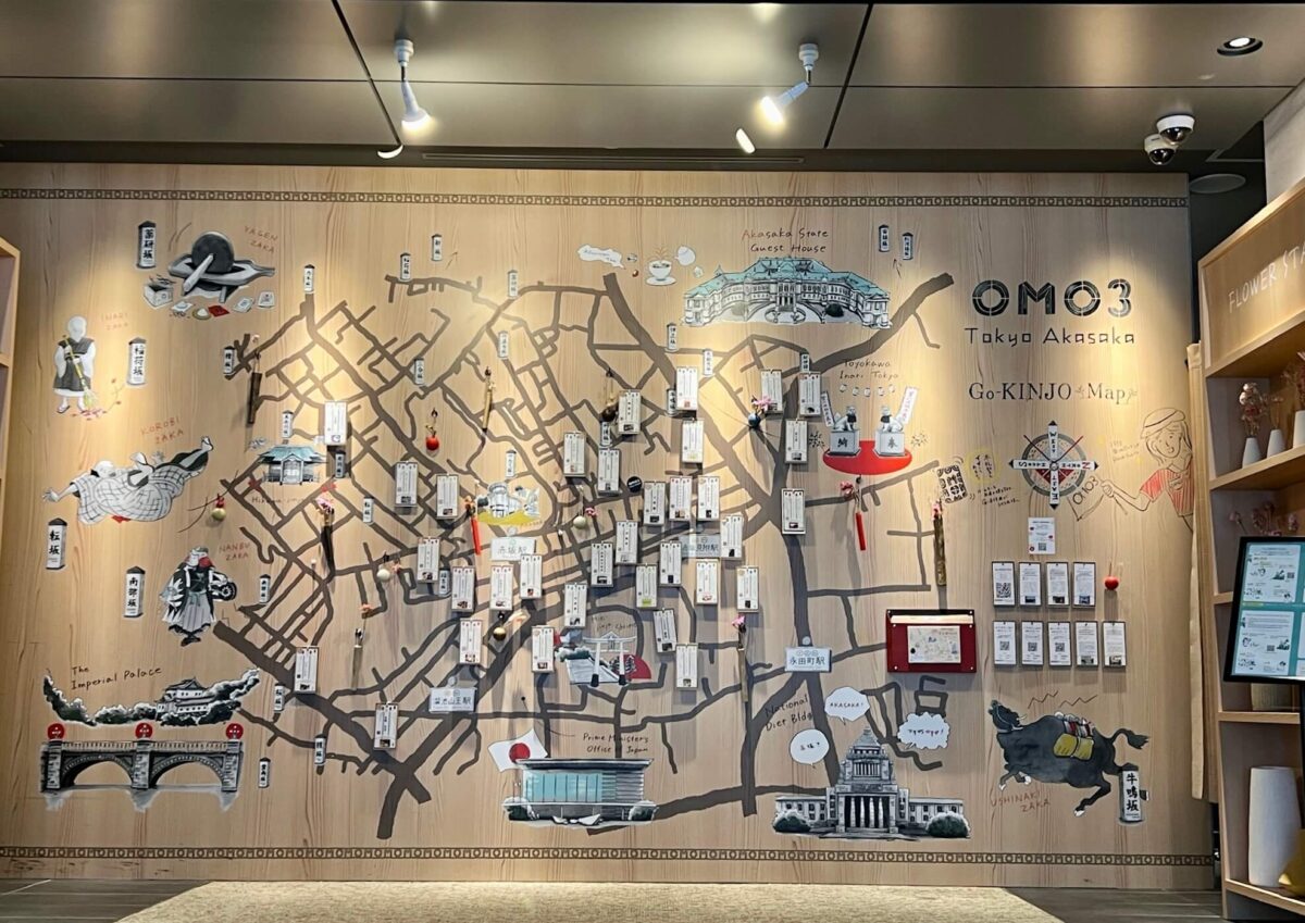 Large wooden wall display featuring a detailed map of Tokyo’s Akasaka district with illustrations of landmarks, directional signs, and decorative art.