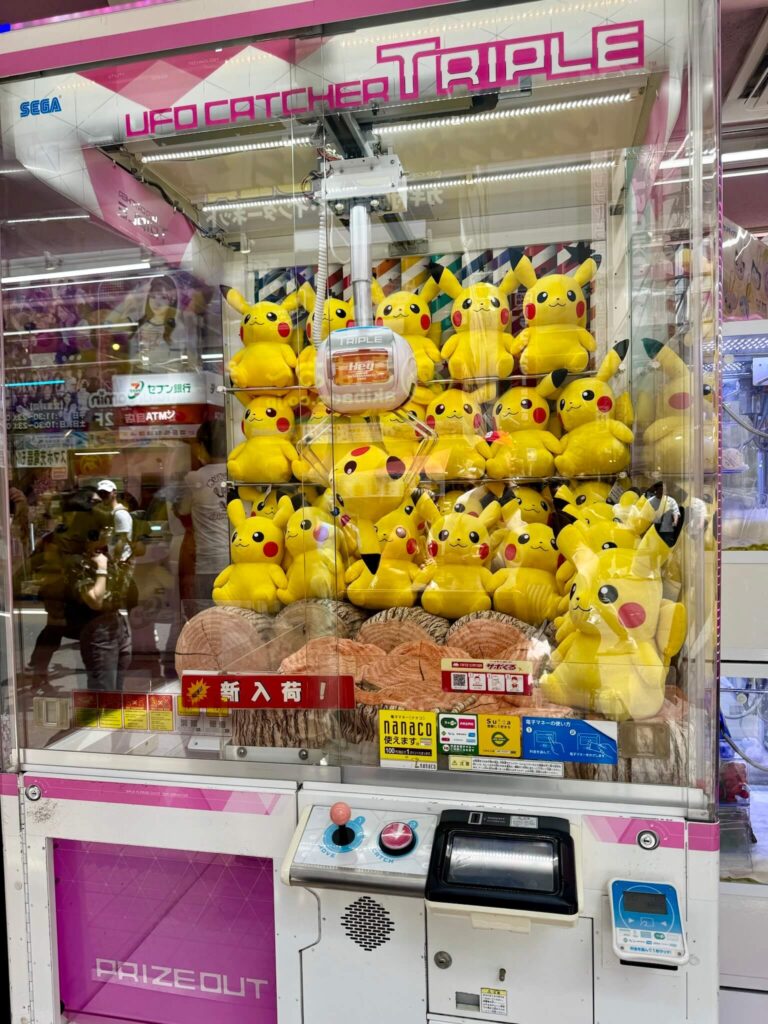 Claw machine filled with Pikachu plush toys at an arcade. The bright yellow Pikachu toys are stacked inside, evoking a playful and lively atmosphere.
