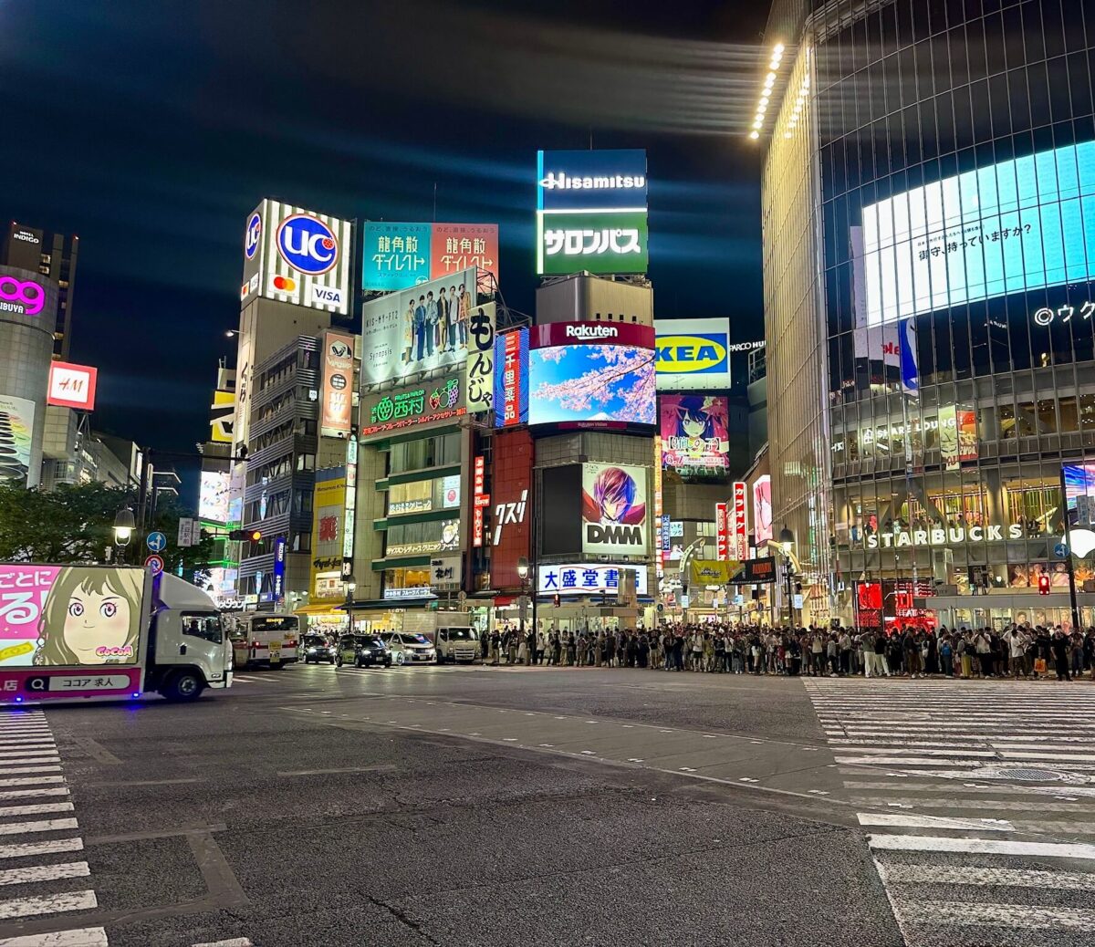 Bustling nighttime scene at Shibuya Crossing, Tokyo, with vibrant billboards, crowded streets, illuminated shops, and a lively, energetic atmosphere.