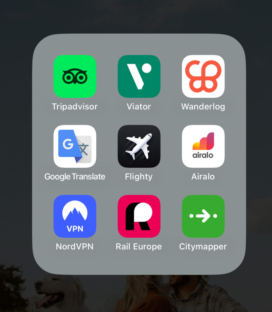 Grid of travel app icons on a phone screen, including Tripadvisor, Viator, Wanderlog, Google Translate, Flighty, Airalo, NordVPN, Rail Europe, and Citymapper.