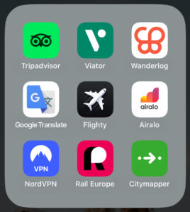 Grid of travel app icons on a phone screen, including Tripadvisor, Viator, Wanderlog, Google Translate, Flighty, Airalo, NordVPN, Rail Europe, and Citymapper.