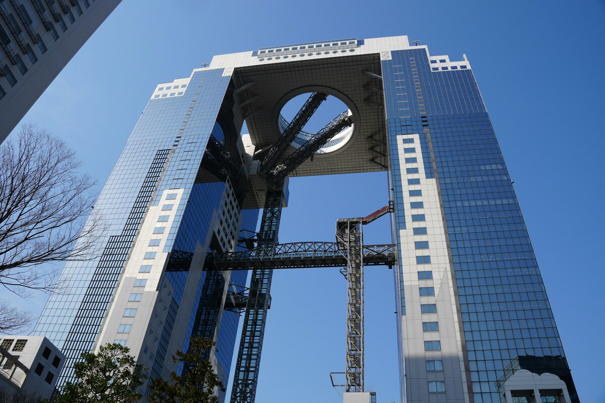 Futuristic Umeda Sky Building in Osaka with two connected towers and glass facade against a clear blue sky. Circular rooftop design adds modernity.