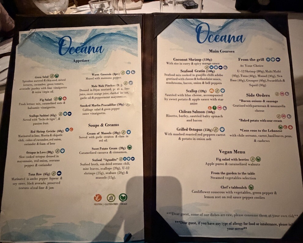 A restaurant menu titled "Oceana" with appetizers, main courses, soups, creams, and a vegan section. Icons denote dietary options like gluten-free and vegan. The menu is visually elegant with a blue and white theme.