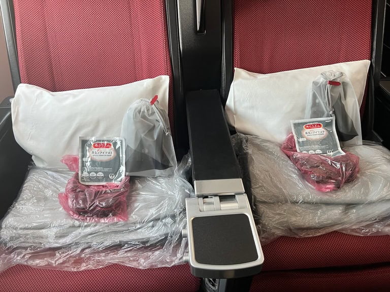 Airplane seat with comfort kit including pillow and blanket for a cozy journey.