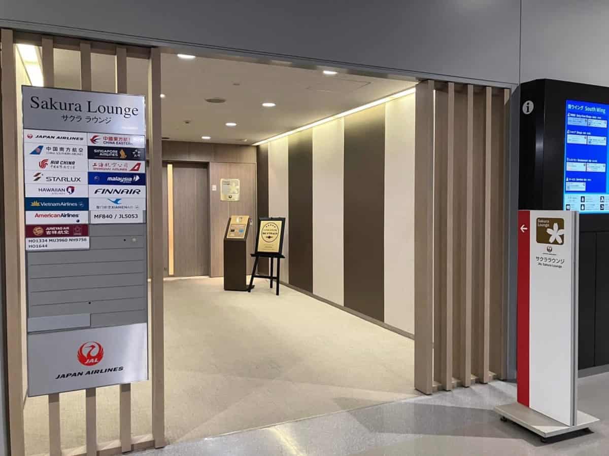 Japan Airlines Sakura Lounge entrance with signage and seating area.
