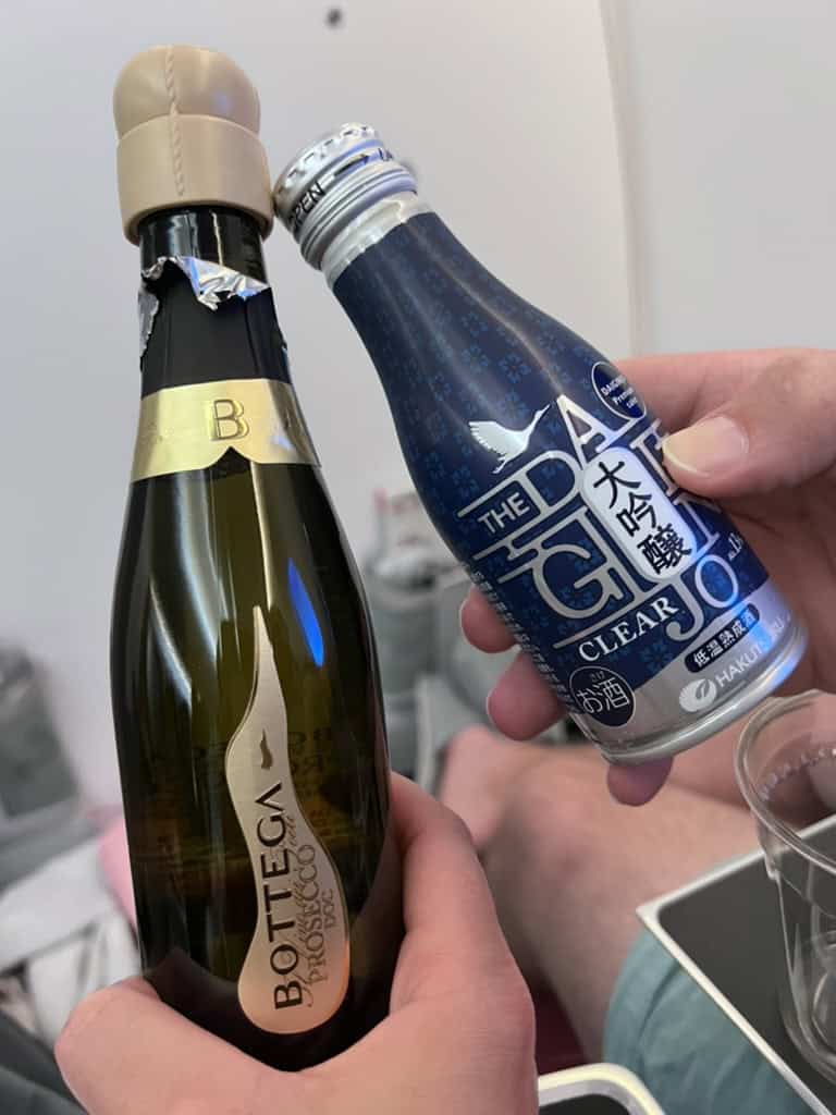 Close-up of champagne and sake bottles being held for celebration.