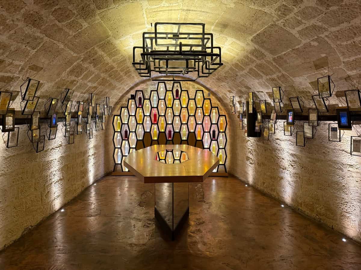Modern art installation in a stone cellar with hexagonal light panels and hanging frames.