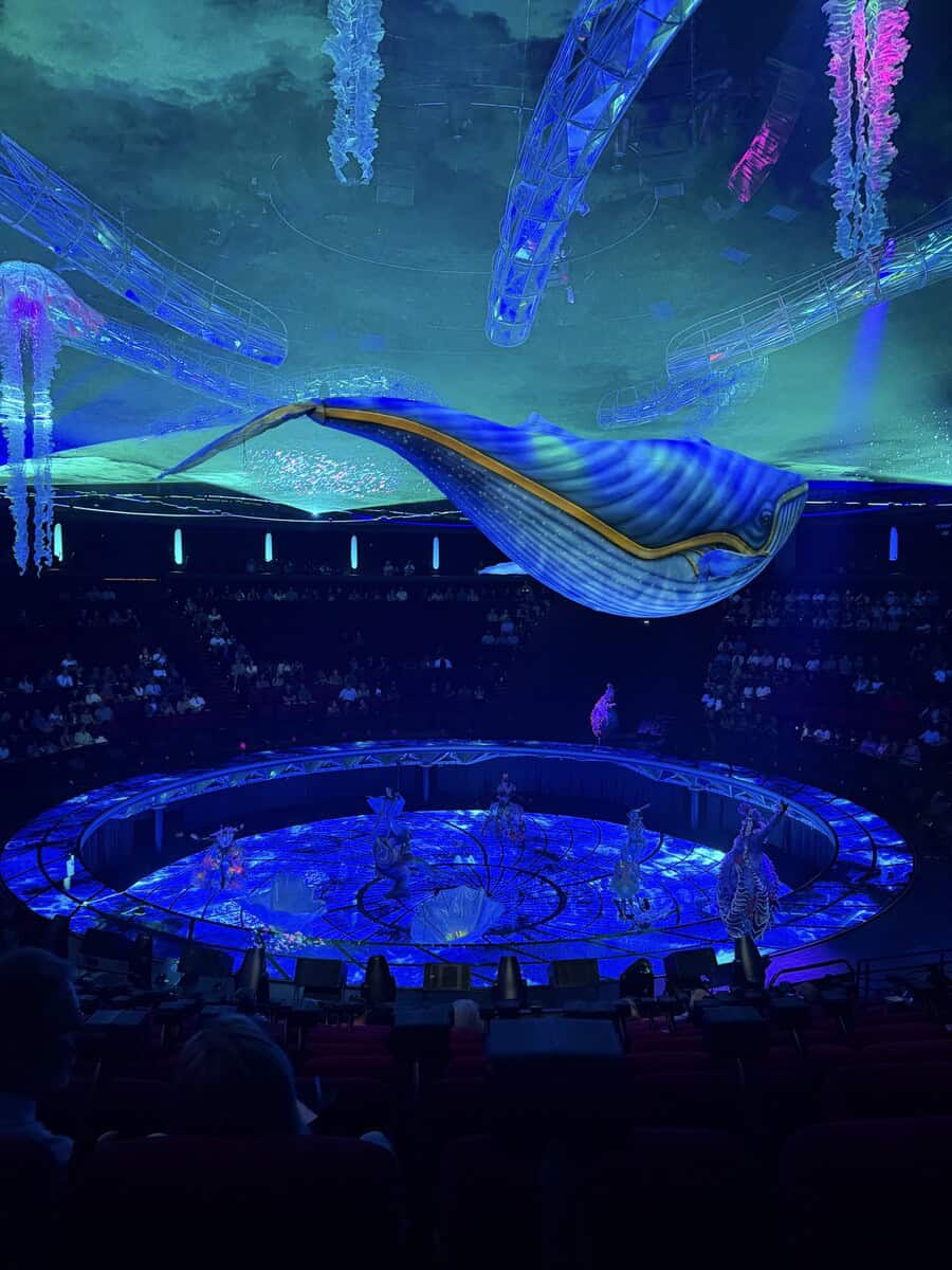Stunning whale-shaped puppet illuminated in vibrant blue at an underwater-themed show.
