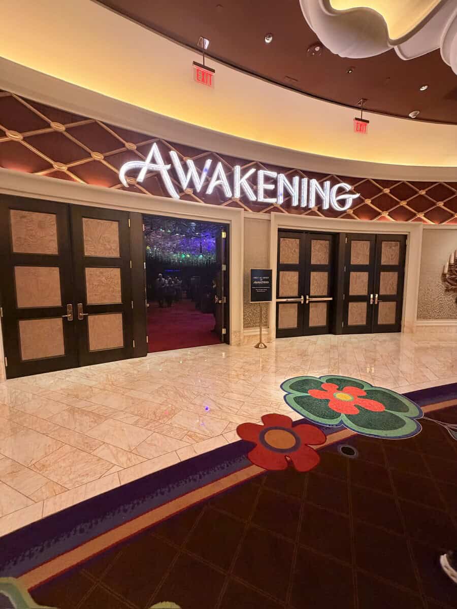 Entrance to Awakening event space with illuminated sign and decorative floral carpet.