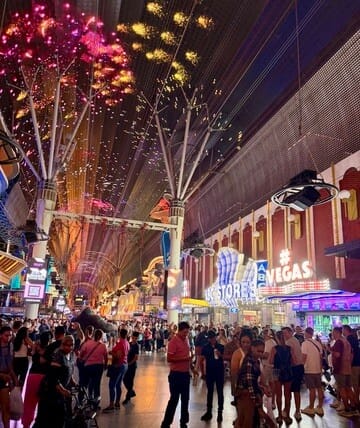 Bright fireworks illuminate the lively Las Vegas Strip at night with crowds enjoying the vibrant atm.