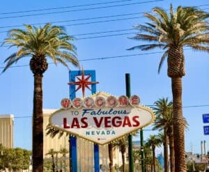 Relaxed Las Vegas welcome sign with palm trees and clear blue sky.