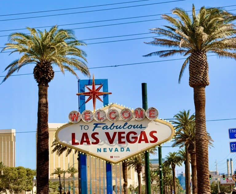 Relaxed Las Vegas welcome sign with palm trees and clear blue sky.