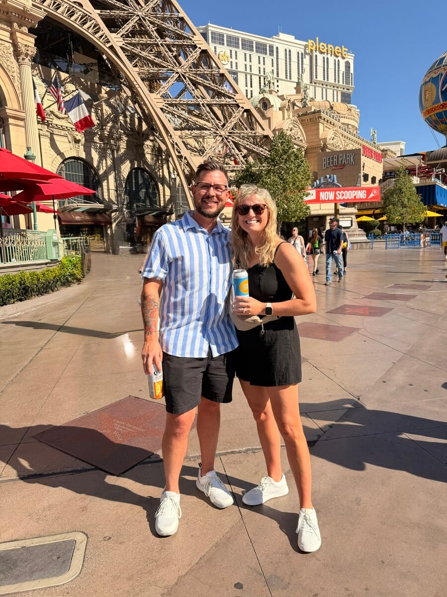 Enjoying a sunny day at an amusement park with rides and attractions in the background.
