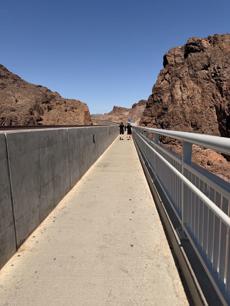 View of Hoover Dam walkway with visitors and rocky canyon walls.