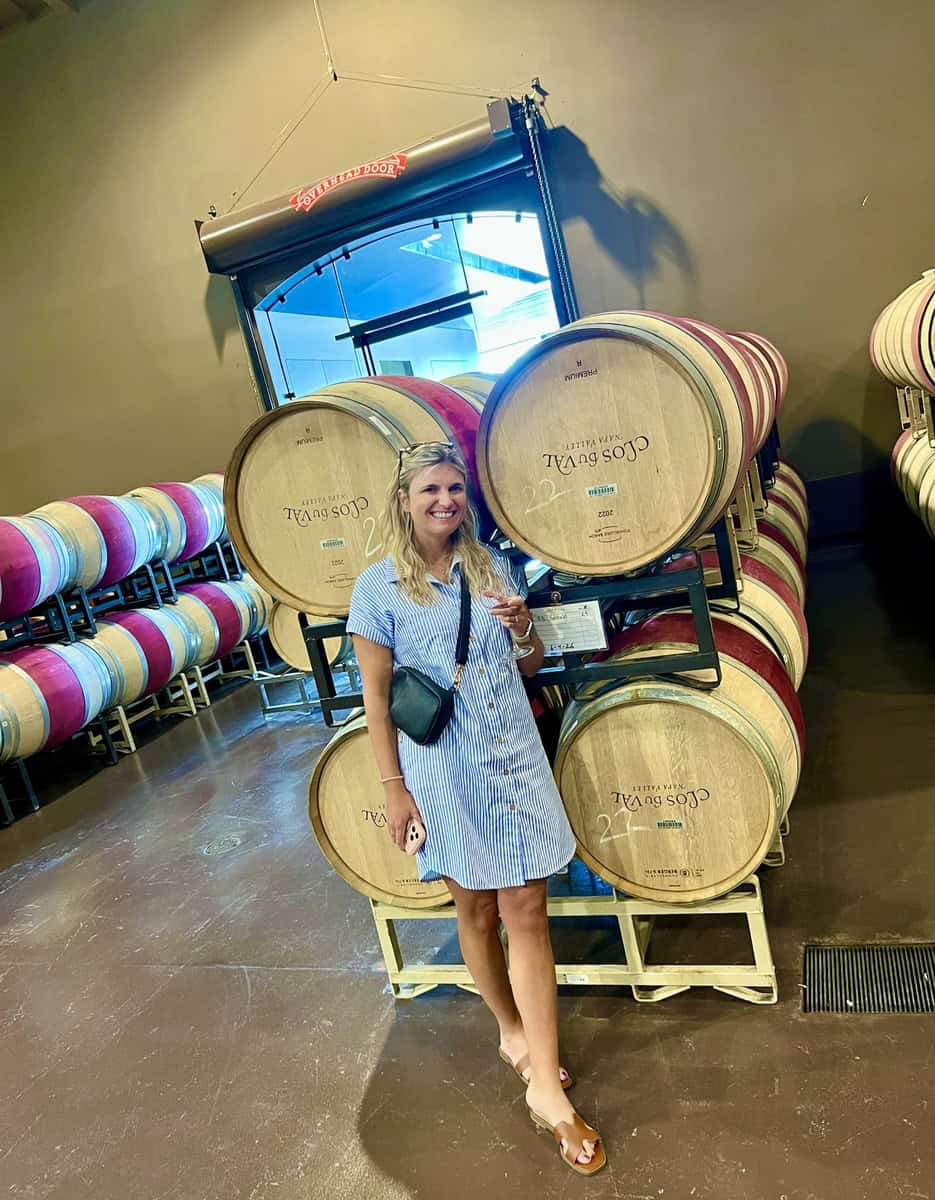 Woman in a blue dress at a wine barrel display in Napa Valley winery.