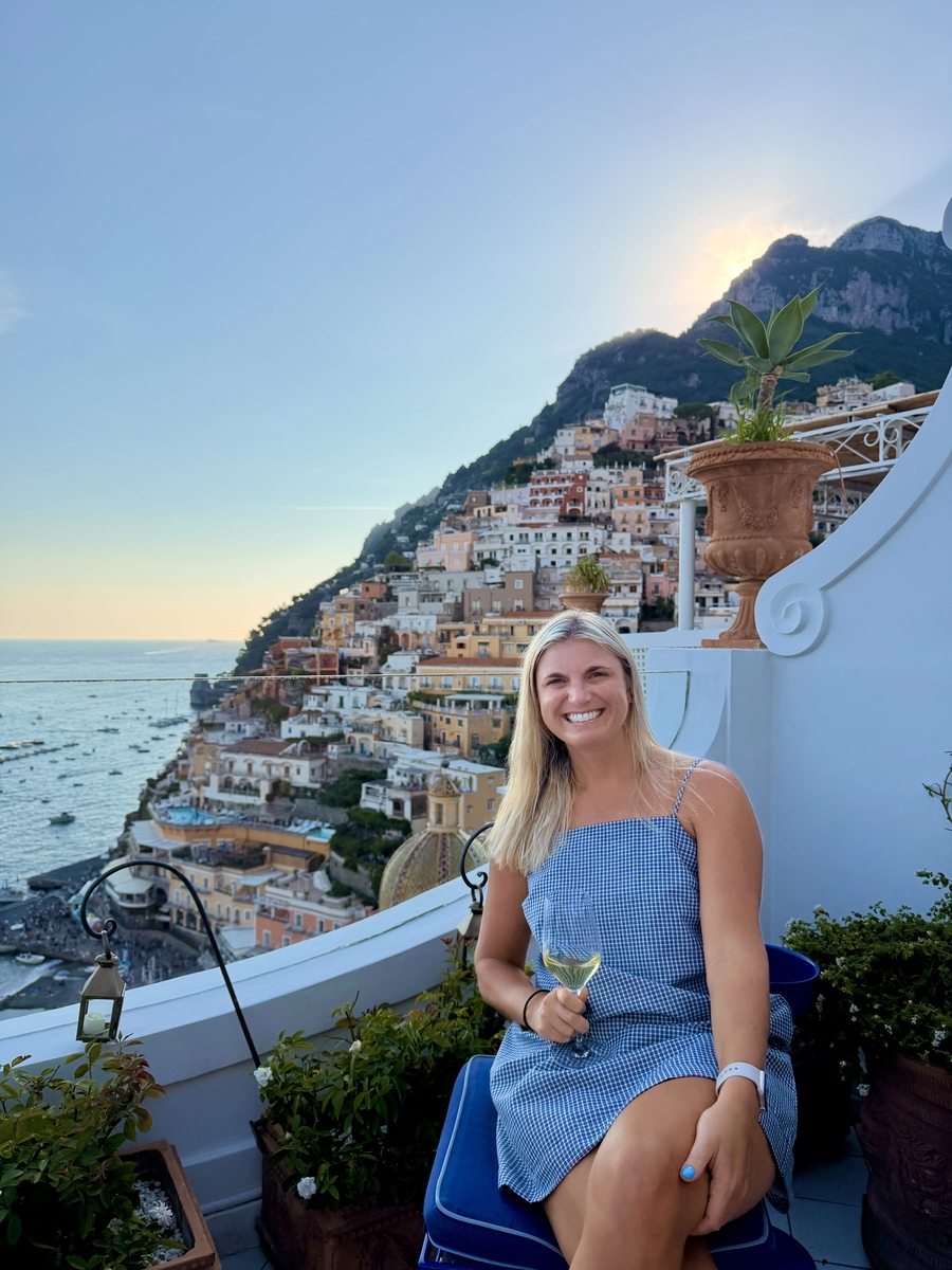 Smiling woman enjoying Amalfi Coast view with colorful buildings.