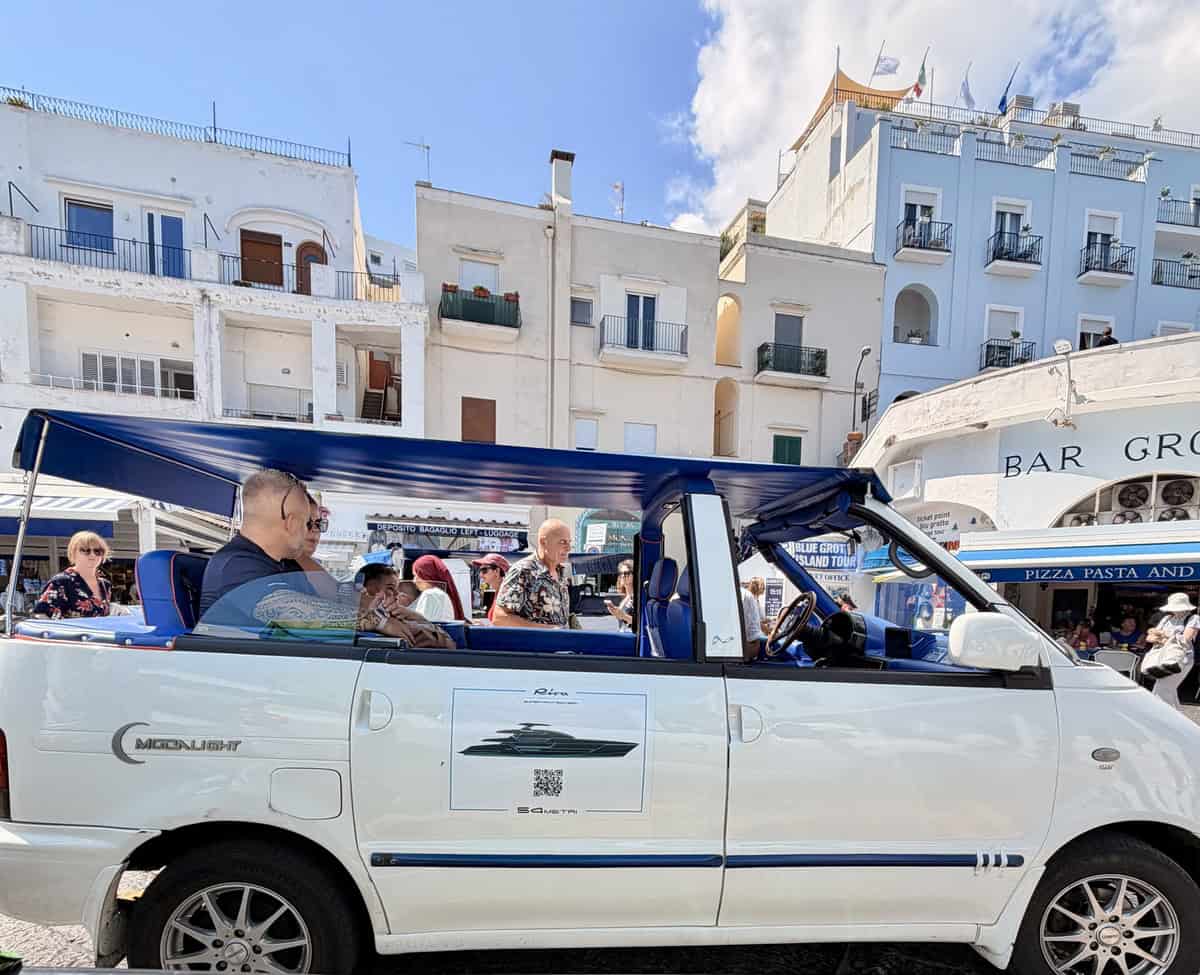 Tourists enjoy a sightseeing tour in a white open-top vehicle in Amalfi Coast, Italy.