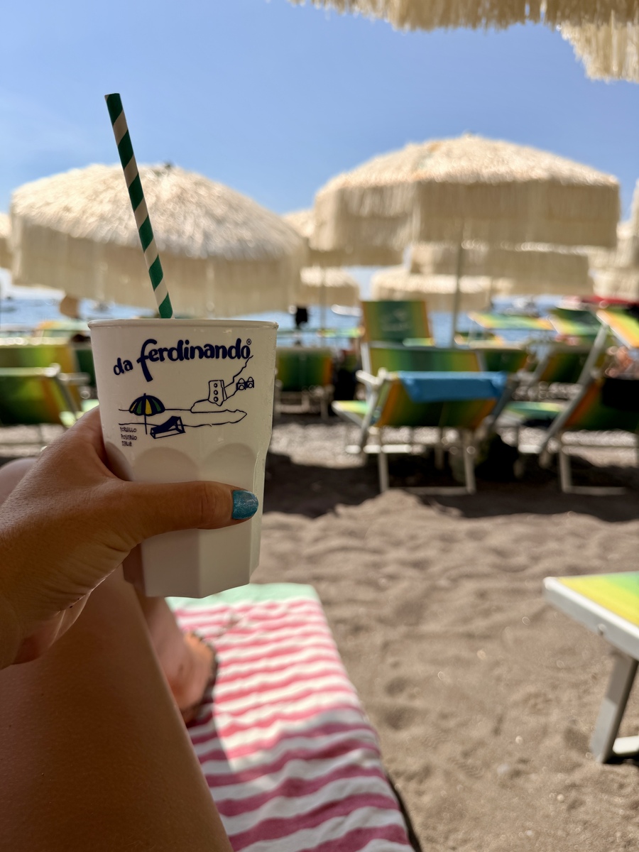 Refreshing drink on a sunny beach with umbrellas and lounge chairs.