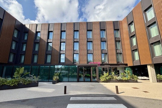 Modern hotel building with wooden facade and glass entrance in Italy.