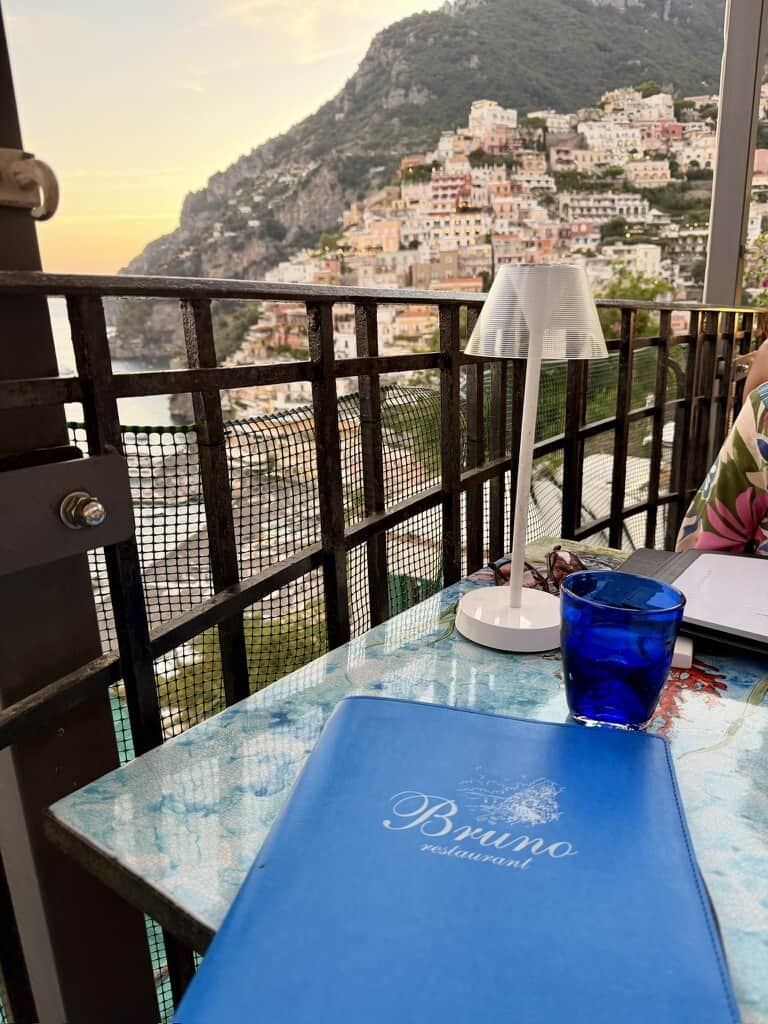 Balcony view of Positano with colorful hillside buildings at sunset.