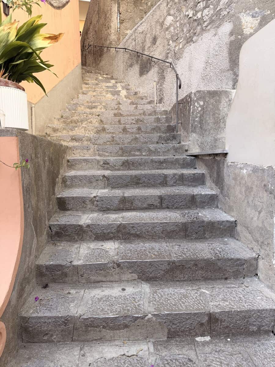 Stone stairs in a historic European town with potted plants nearby.