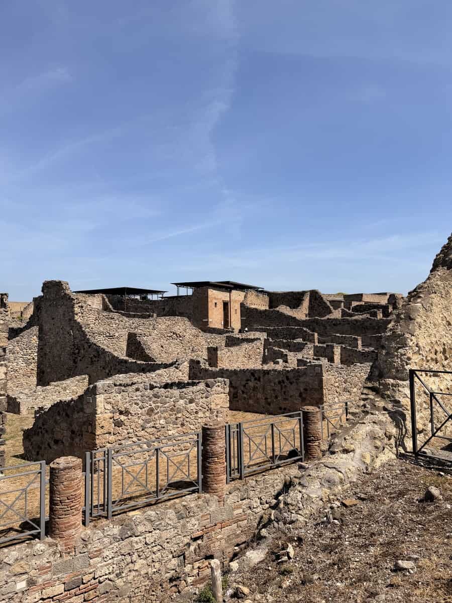 Ruins of Pompeii archaeological site with stone structures and clear blue sky.